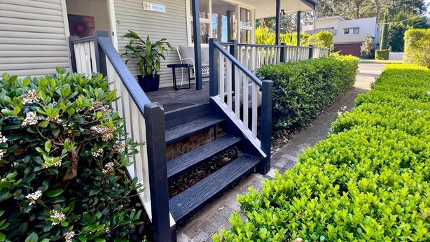 A two-story house with a covered porch, a staircase, and a well-maintained garden.