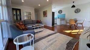 A modern living room with a grey sofa, a coffee table, and a dining area with a table and chairs.