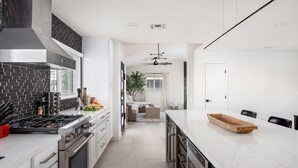 Una cocina moderna con una isla grande, horno empotrado y salpicadero de azulejos negros.