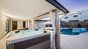 Un jacuzzi con vistas a una piscina y un edificio moderno al fondo.