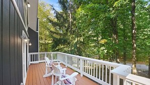 Eine Holzterrasse mit weißen Geländern und zwei Adirondack-Stühlen.