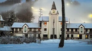 Ein Gebäude mit einem zentralen Turm, zahlreichen Fenstern und einem mit Schnee bedeckten Dach.
