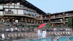 Ein Hotel mit Poolbereich, Außenbereich zum Sitzen und einem mehrstöckigen Gebäude mit Balkonen.