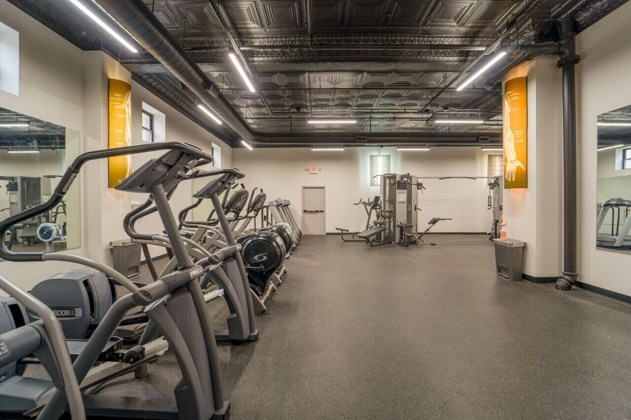Une salle de sport équipée de tapis de course, d’appareils de musculation et de miroirs.