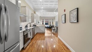 A modern kitchen with stainless steel appliances, wooden flooring, and a view to the living area.