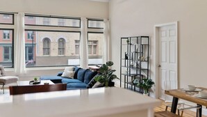 A modern living room with a sofa, a coffee table, and a dining area with a wooden table and chairs.