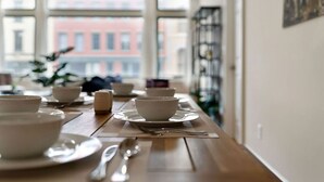 A dining table set with white bowls and plates, a candle, and a fork.