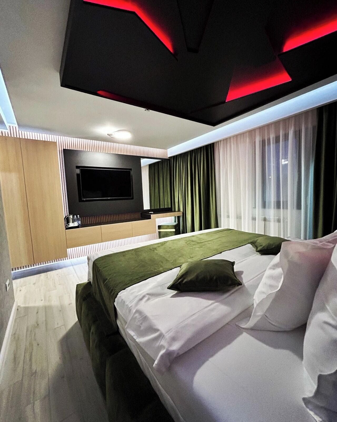Ein modernes Hotelzimmer mit einem Bett, einem Fernseher und einer Küchenzeile.