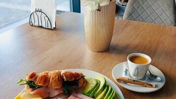 A table with a plate of food, a cup of coffee, and a vase of flowers.
