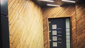 Un pasillo con paneles de madera y piso de baldosas que conduce a una puerta con vidrios esmerilados.