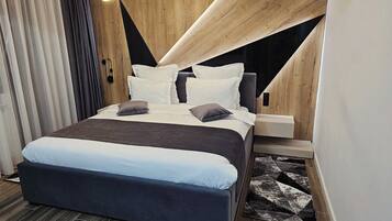 A modern bedroom with a bed, bedside tables, and a unique geometric wall design.