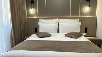 A neatly made bed with white and brown bedding, two wall-mounted reading lights, and a headboard with vertical lines.