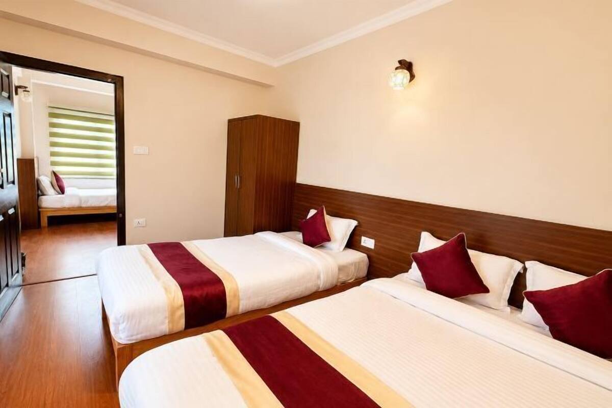 A hotel room with two beds, a wardrobe, and a mirror.