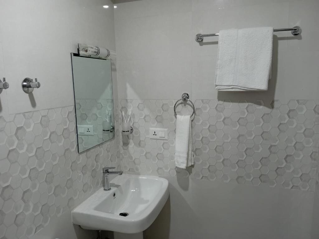 A bathroom with a white sink, a mirror, a towel rack, and hexagonal patterned walls.