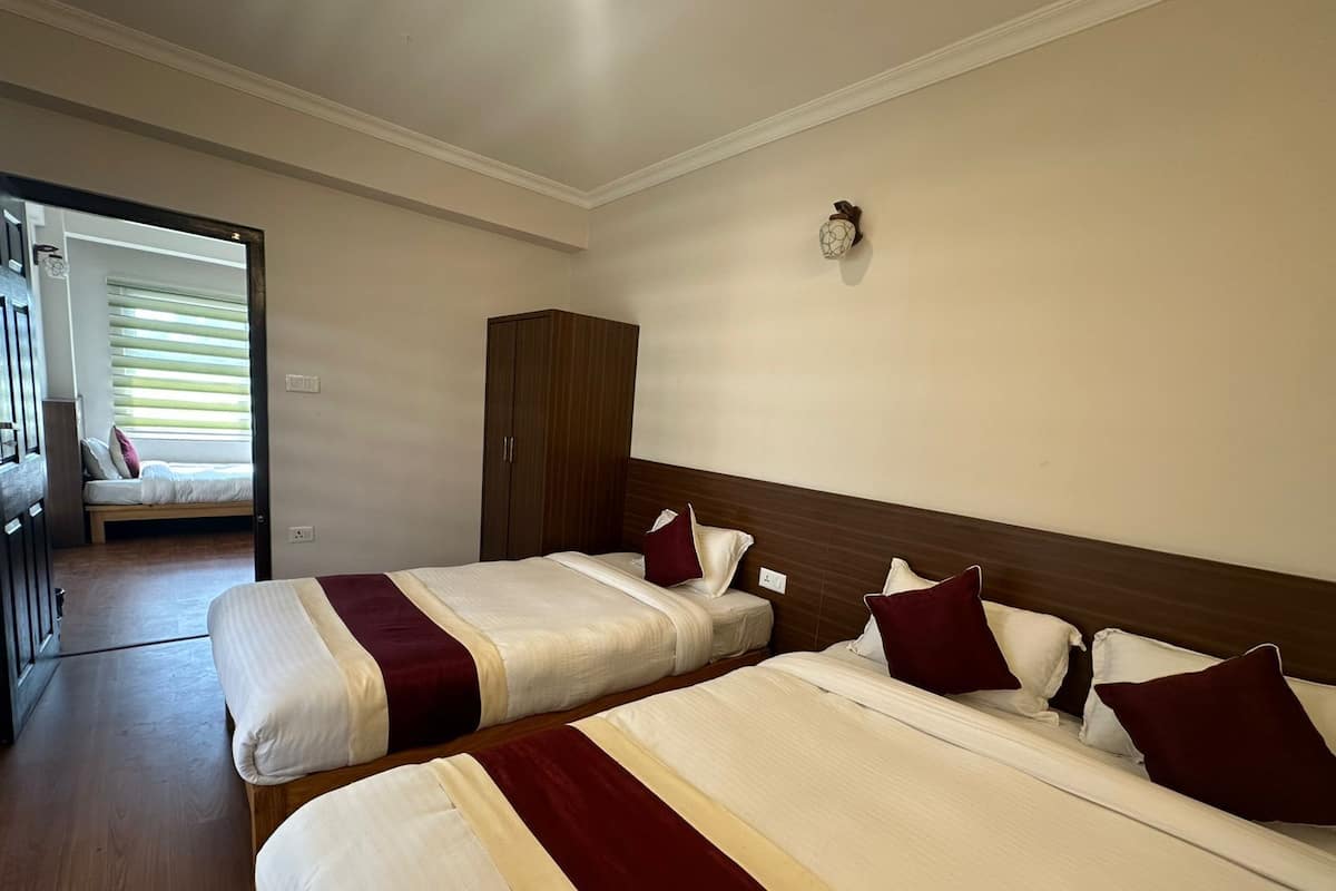A hotel room with two beds, a wardrobe, and a window with blinds.