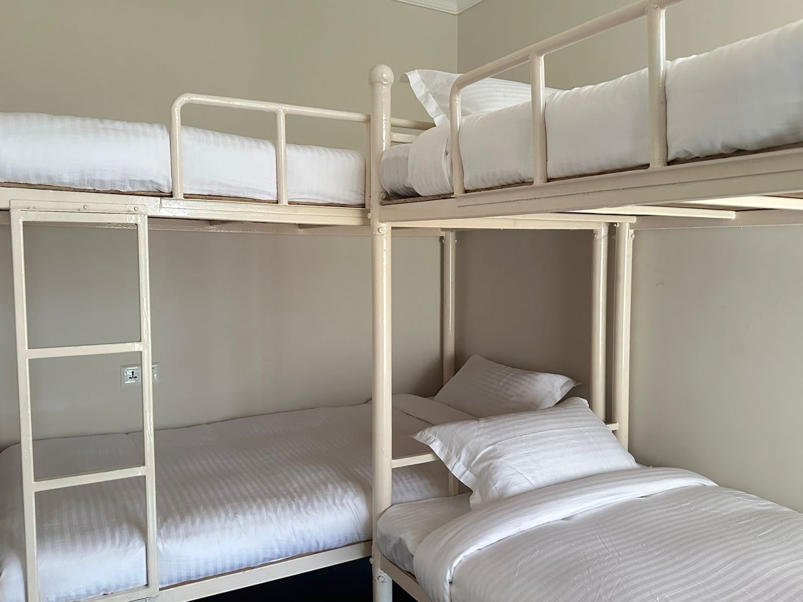 A bunk bed room with two levels, each with a mattress and pillows.
