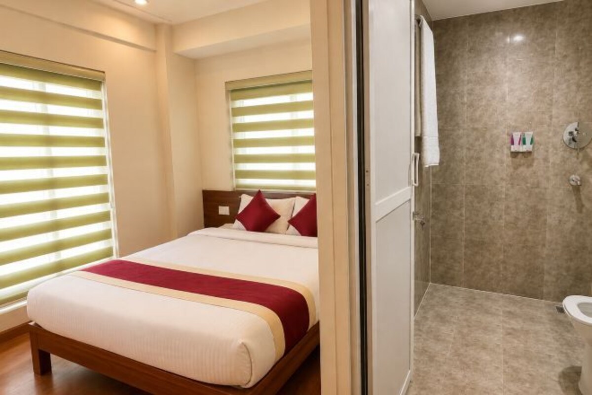 A hotel room with a bed, a shower, and a toilet.