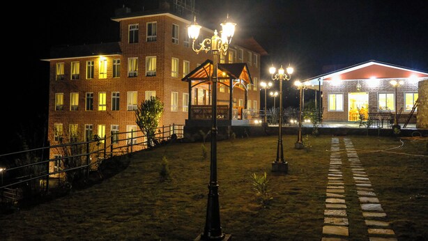 A brick building with multiple windows and a well-lit entrance. - Hotel Dolkha Durbar (Bhimeshwar)