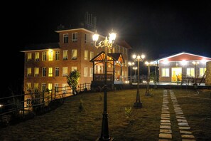 A brick building with multiple windows and a well-lit entrance. - Hotel Dolkha Durbar  (Bhimeshwar)