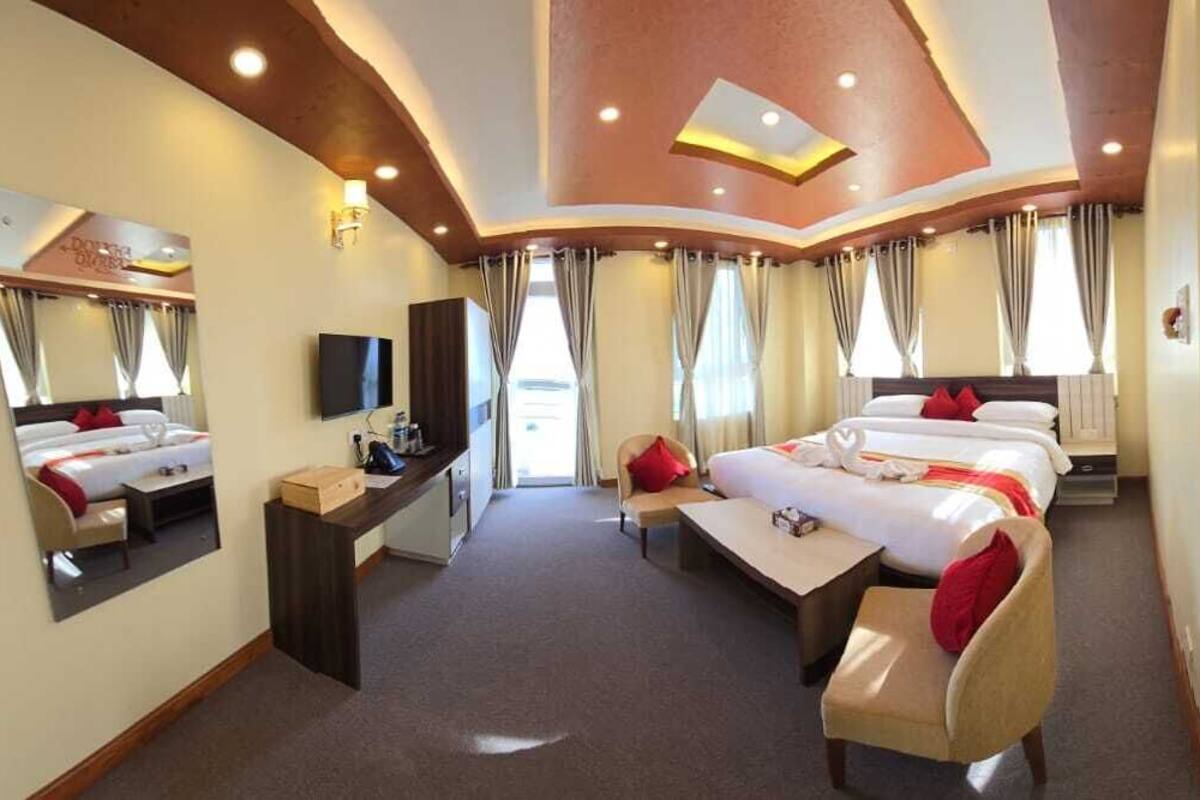 A hotel room with a large bed, a desk, a chair, a TV, and a bathroom.