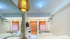 Una habitación de hotel moderna con dos camas, un espejo grande, una lámpara colgante y un banco de madera.