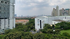 A high-rise building with multiple floors and balconies, surrounded by greenery and other buildings. - Minimalist Studio Apartment at Springhill Terrace Residence (Jakarta)