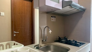 A compact kitchen with a stainless steel sink, a faucet, and a gas stove. - Minimalist Studio Apartment at Springhill Terrace Residence (Jakarta)