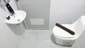 Un baño con un lavamanos blanco, un inodoro y una toalla sobre el asiento.