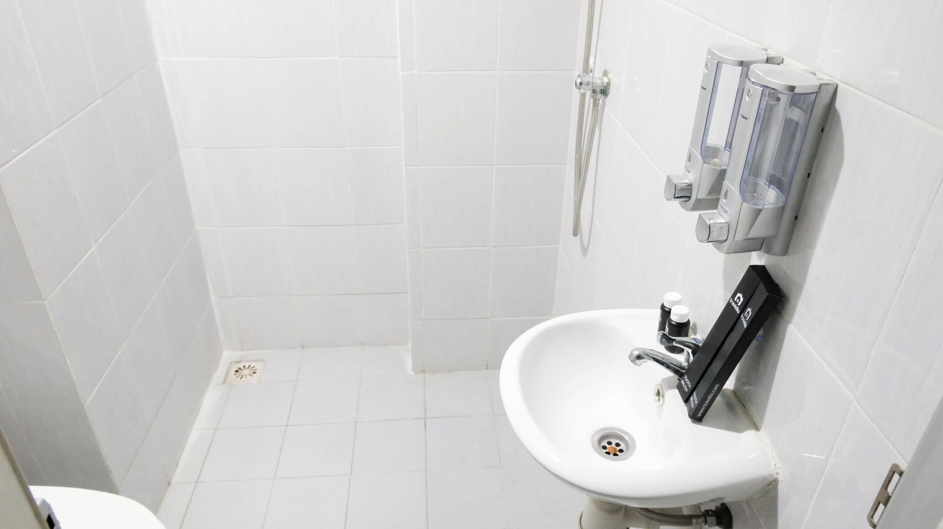 A small, white bathroom with a sink, a shower, and a toilet.