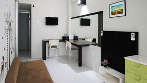 Una habitación pequeña y moderna con un escritorio, dos sillas, un mueble negro y un espejo grande.