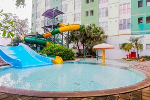 Una piscina con tobogán y zona de juegos infantiles.