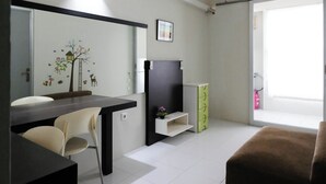 Un espacio habitable compacto con una mesa de comedor, sillas, un sofá, un mueble para televisor y una estantería pequeña.