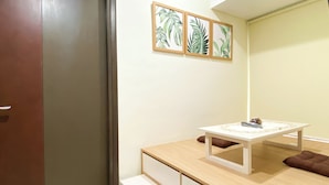 Um quarto pequeno e bem organizado, com uma mesa de madeira, um armário branco e uma porta.