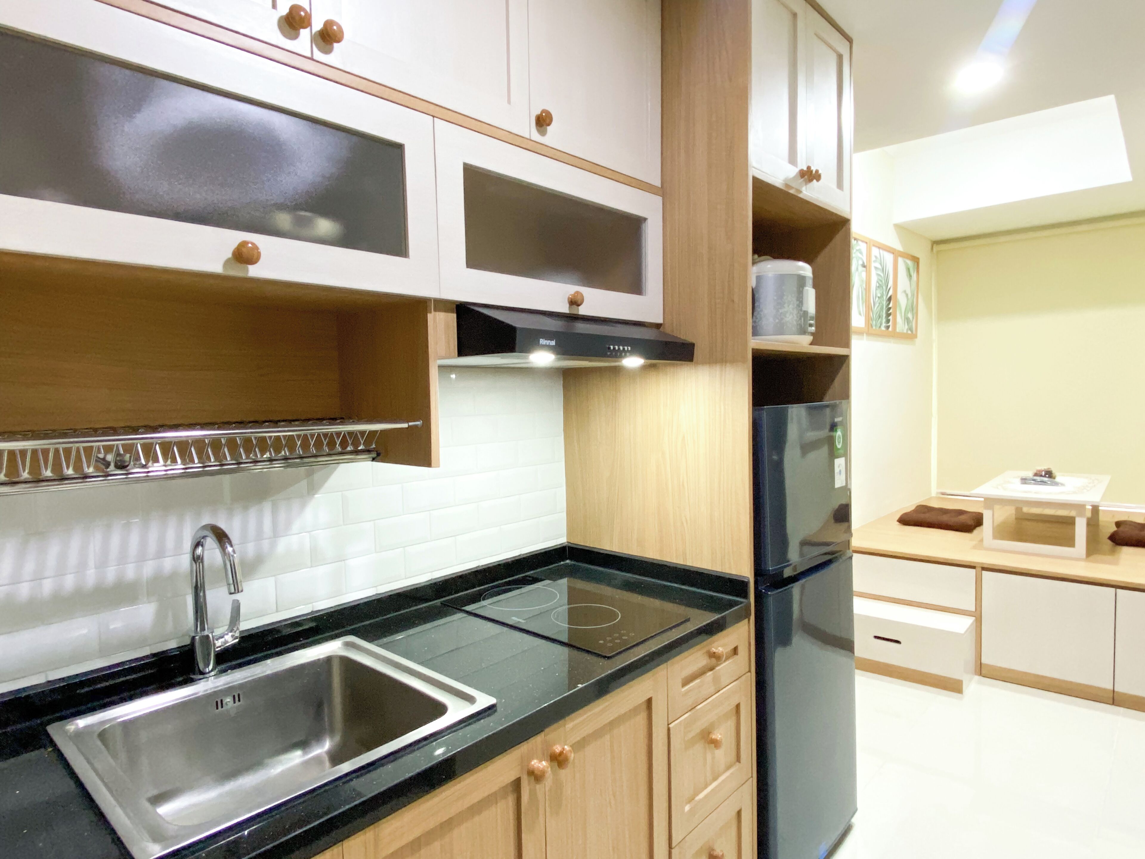 Una cocina moderna con un lavamanos de acero inoxidable, armarios de madera y un refrigerador negro.
