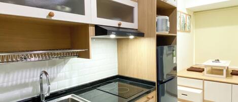Una cocina moderna con un lavamanos de acero inoxidable, armarios de madera y un refrigerador negro.