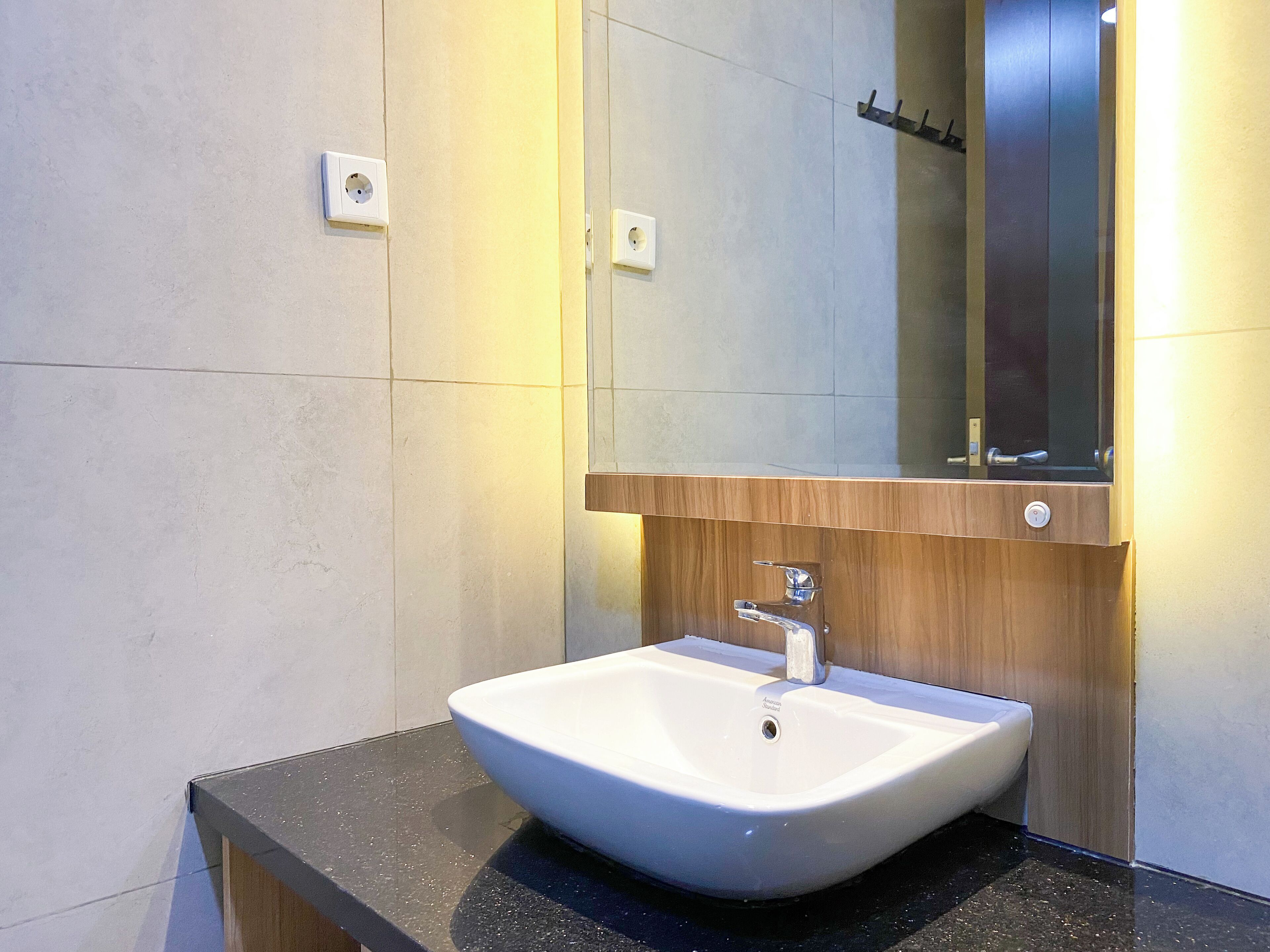 A modern bathroom with a white sink, a wooden vanity, and a mirror above the sink.