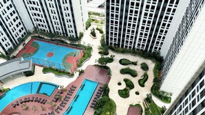 Um edifício alto com piscina no terraço e quadra de basquete.