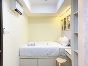 Cozy retreat with a single bed, skylight, and air conditioning unit.