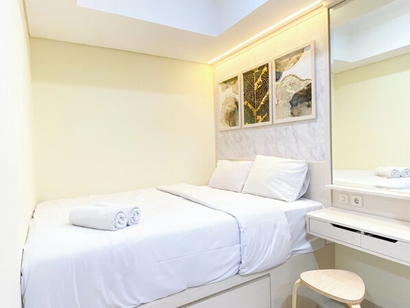 A hotel room with a bed, a bedside table, a mirror, and artwork on the wall.