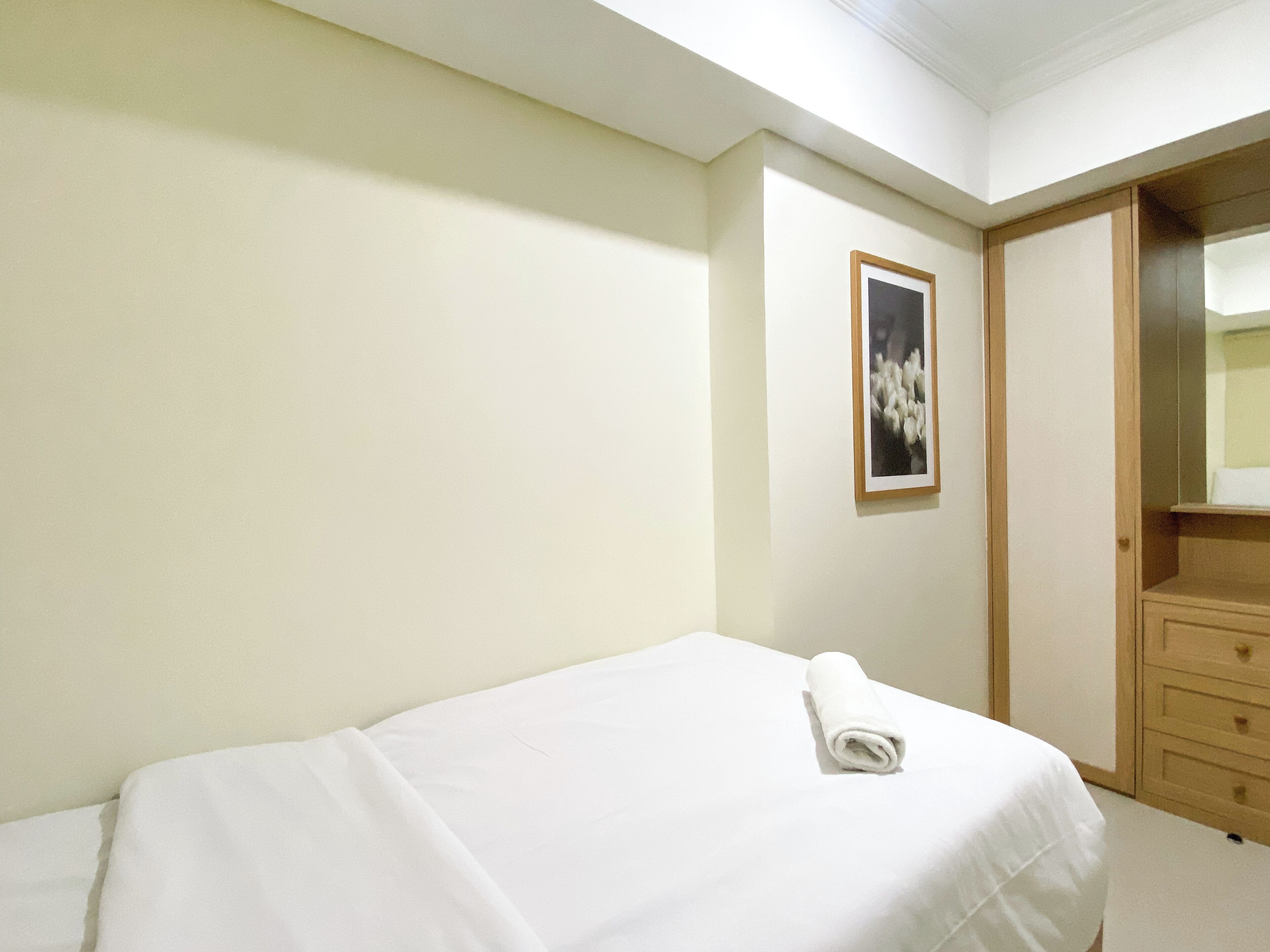 Ein Schlafzimmer mit einem Bett, einem Holzschrank und einem gerahmten Bild an der Wand.