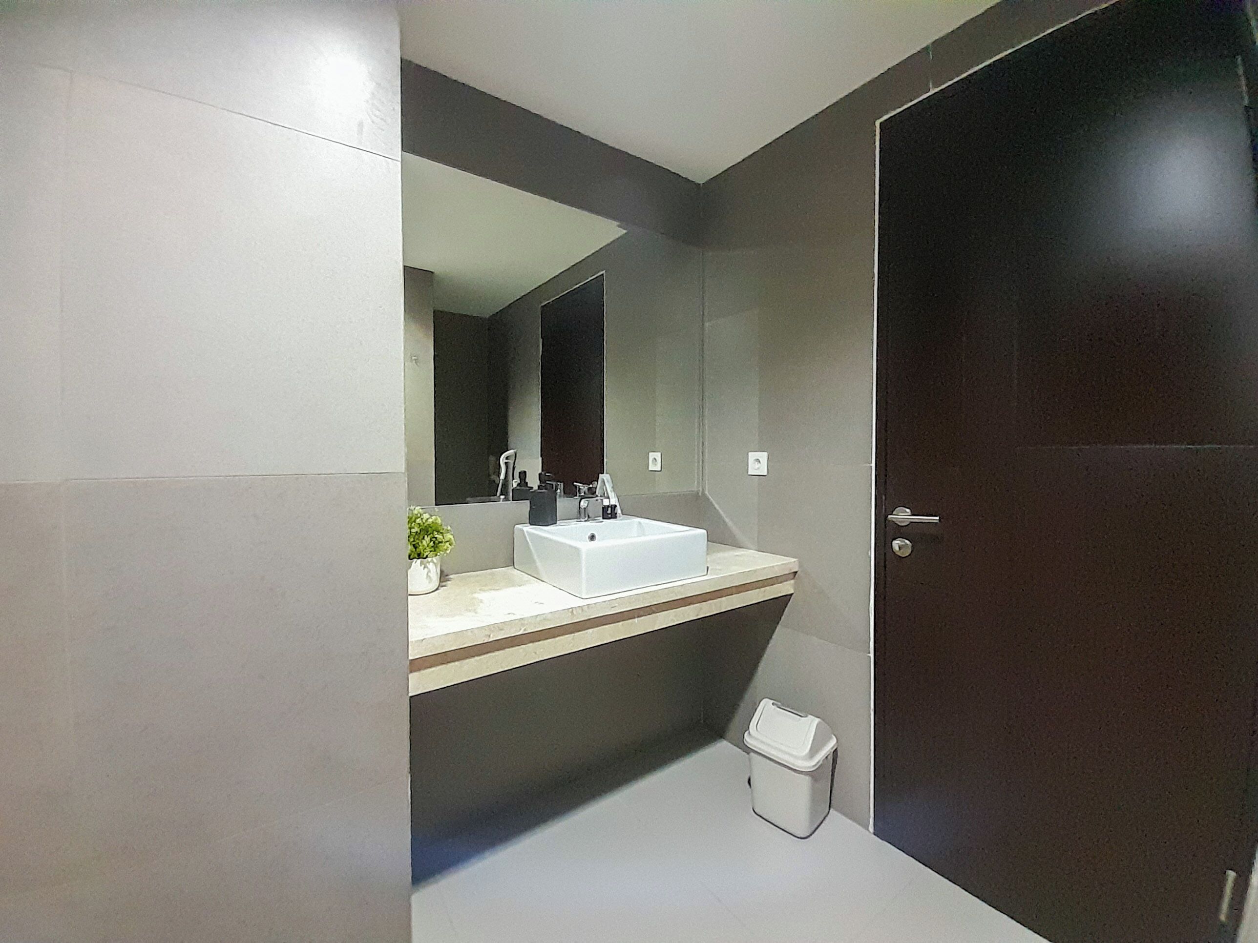 A modern bathroom with a white sink, dark walls, and a large mirror.