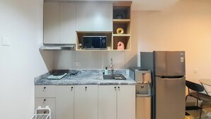 A compact kitchen with a microwave, sink, and refrigerator. - Comfort Stay 1BR at Patraland Amarta Apartment (Ngaglik)