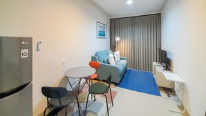 A compact living space with a kitchenette, a sofa, a dining table, and a TV. - Comfort Stay 1BR at Patraland Amarta Apartment (Ngaglik)