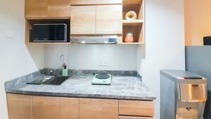 Cozinha com armários de madeira, micro-ondas, torradeira e dispensador de água.
