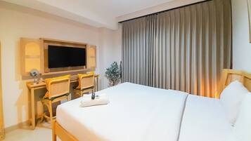 Una habitación de hotel con una cama grande, un escritorio con una silla, un televisor y una ventana con cortinas.