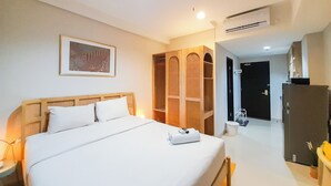 Quarto de hotel com uma cama grande, um guarda-roupa, um espelho e um ar condicionado.