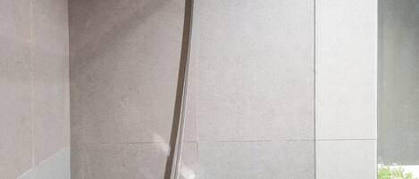 A shower with a hose and a faucet in a tiled bathroom.