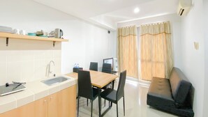 A compact kitchen with a sink, a dining table with chairs, a sofa, and a television. - Homey and Modern 2BR Apartment at Royal Olive Residence (Jakarta)