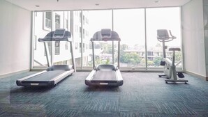 A fitness room with treadmills, a stationary bike, and a rowing machine. - Homey and Modern 2BR Apartment at Royal Olive Residence (Jakarta)