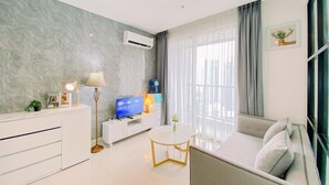 A modern living room with a sofa, a TV, a small table, and a lamp.